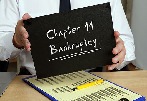 Person holding Chapter 11 Bankruptcy sign; legal advice for corporate bankruptcy. - Wayne Greenwald, P.C.